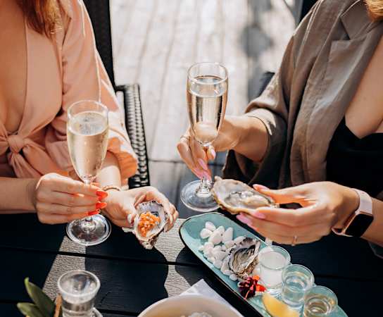 three women sitting at a table with plates of oysters and glasses of champagne at 511 Meeting, South Carolina