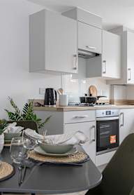 a modern kitchen with grey cabinets and black appliances