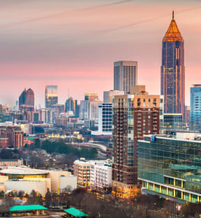 a city skyline at sunset with a pink sky and skyscrapers at Atler at Brookhaven, Atlanta, GA