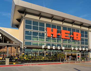 The exterior of a HEB Fresh Foods store with a clear blue sky in the background.