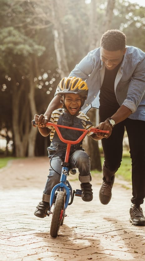 a man helping a young boy ride a bike at The Grove Germantown in Germantown, Tennessee