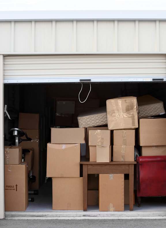 A storage unit with boxes and a red bin visible.