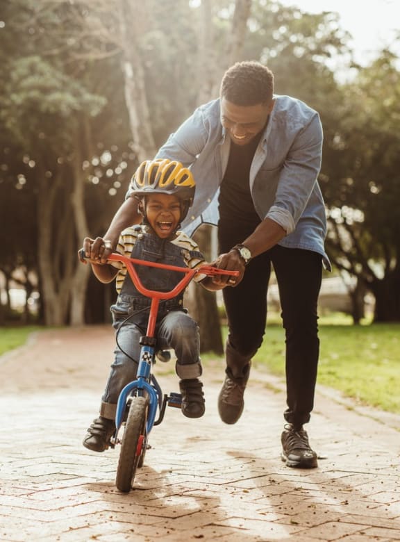 a man helping a young boy ride a bike at Tara Oaks in Houston, TX