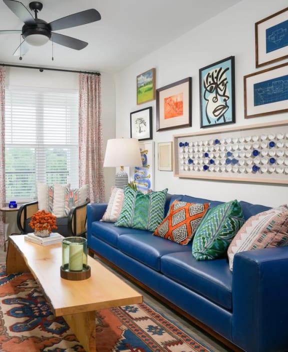 a living room with a blue couch and a ceiling fan at The Eddy at Riverview, Smyrna, GA
