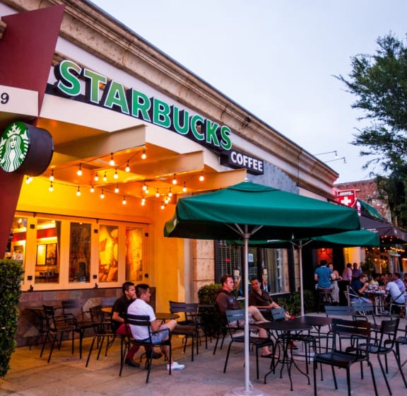 people sitting at tables outside of a starbucks coffee restaurant
