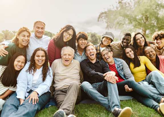 A group of people sitting on the grass in a park.
