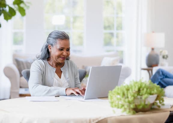 a woman sitting at a table using a laptop computer