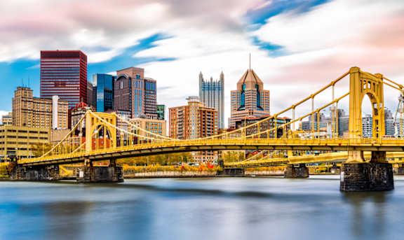 A city skyline with a yellow bridge crossing a river.