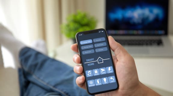 a man holding a smartphone with the smart home app on the screen