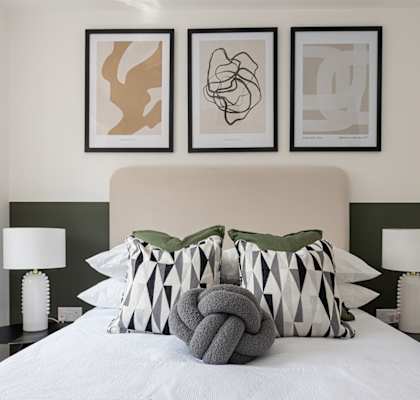 a bedroom with a bed with pillows and pictures on the wall above it