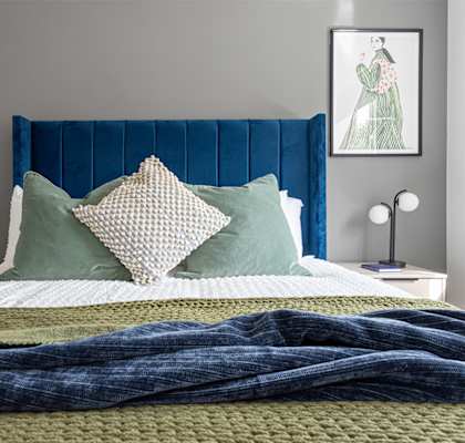 a bedroom with a bed with blue and green pillows    and a