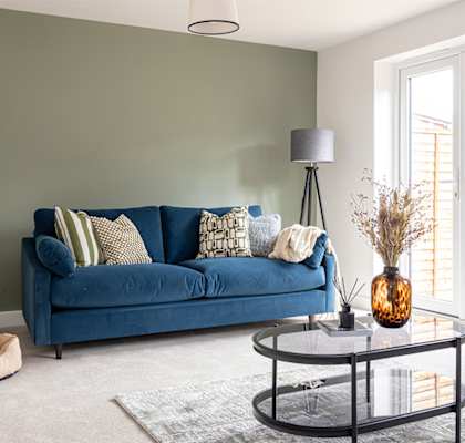 A blue couch with a black metal coffee table in front of it.