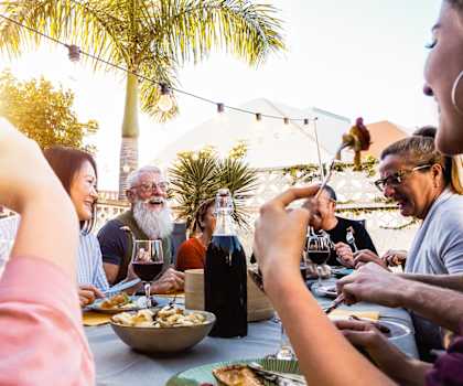 a group of people sitting around a table eating food and drinking wine at The District at Rosemary, Sarasota, Florida