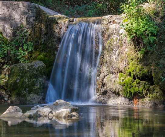a small waterfall over a river in a forest at Northland at the Arboretum, Austin, Texas