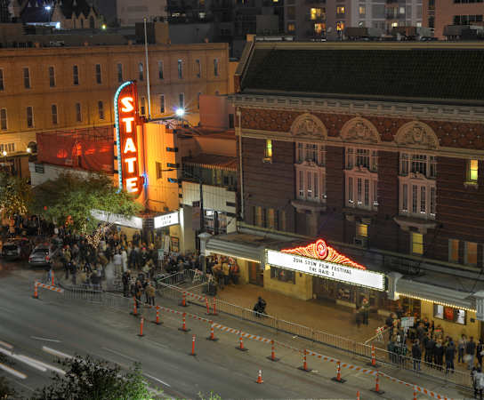 a city street at night with people walking around and a theater sign in the background at Monterey Ranch, Austin, Texas