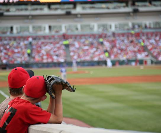 a young boy in a red baseball uniform takes a picture of a baseball game at Promenade at Reflection Lakes, Florida, 33907