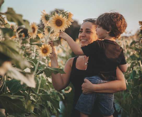 a woman holding a child in a field of sunflowers at Monterra at Bonita Springs, Bonita Springs, Florida
