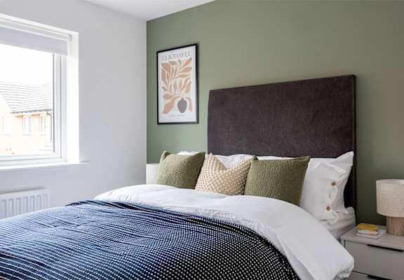 A bedroom with a large bed and a picture on the wall.