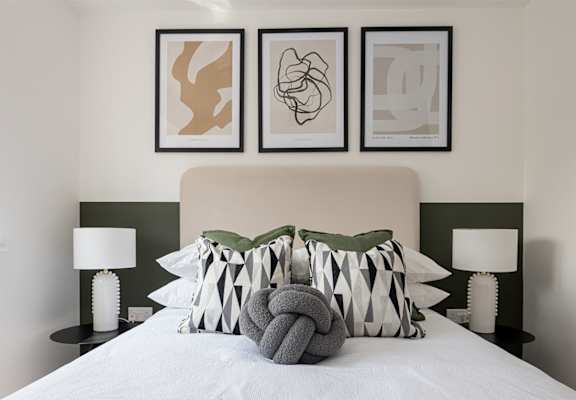 a bedroom with a bed with pillows and pictures on the wall above it