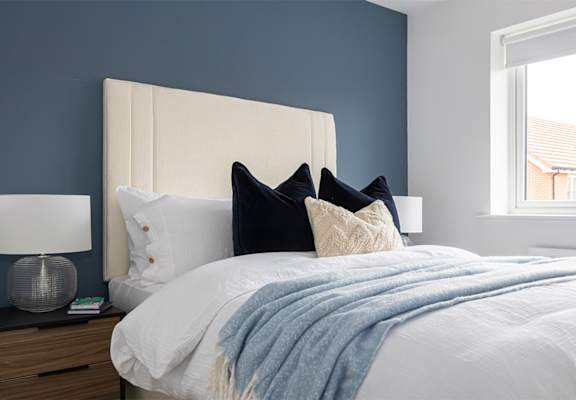 a bedroom with blue walls and a white bed with pillows