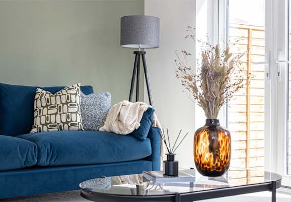 a living room with a blue couch and a table and a lamp