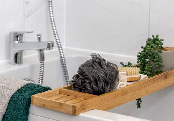 a wooden tray with soap and a wash cloth on a bathroom sink