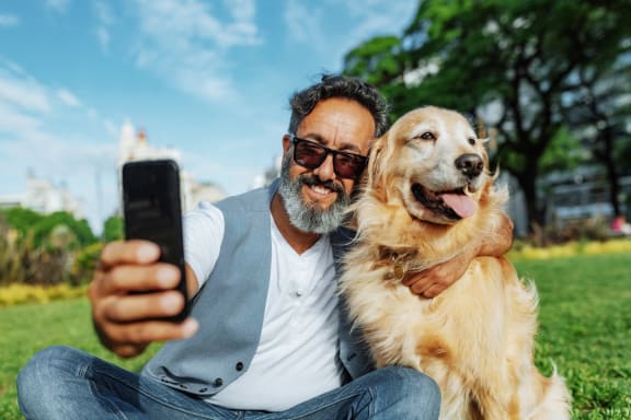 a man and his dog taking a picture with a cell phone