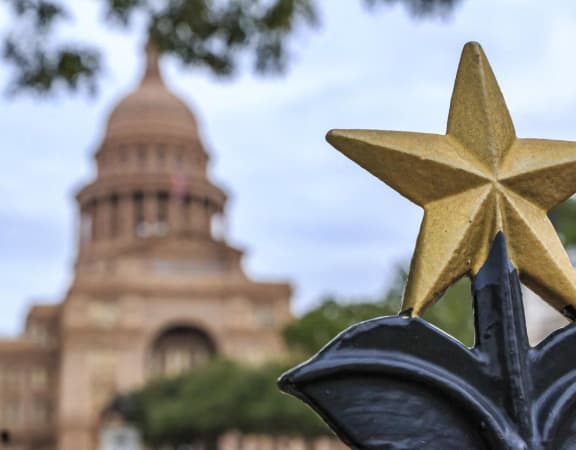 a gold star on a fence with a building in the background