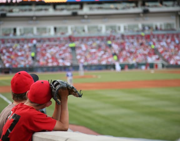 a young boy in a red baseball uniform takes a picture of a baseball game