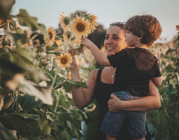 a woman holding a child in a field of sunflowers