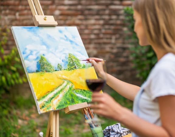a woman painting a landscape on an easel