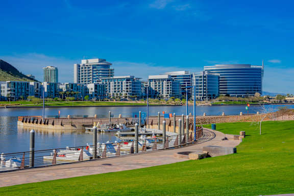 A cityscape with a body of water and boats docked at a pier.