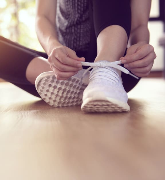 a woman is sitting on the floor with her legs crossed and tying her shoe at Parke Place, Prescott Valley, Arizona