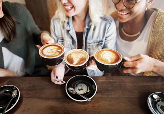 three women holding coffee cups in their hands over a table