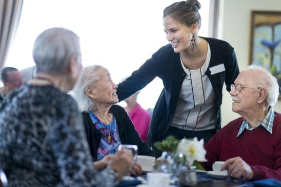 a caregiver talking to seniors at a table