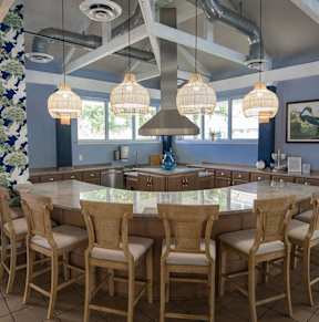 A kitchen with a large island and chairs.
