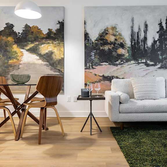 A living room with a white couch and a painting on the wall.