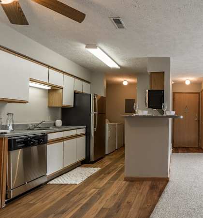 A kitchen with wooden floors that opens to living room