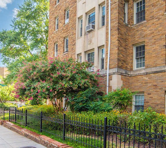 A tall brick building with a black fence in front.