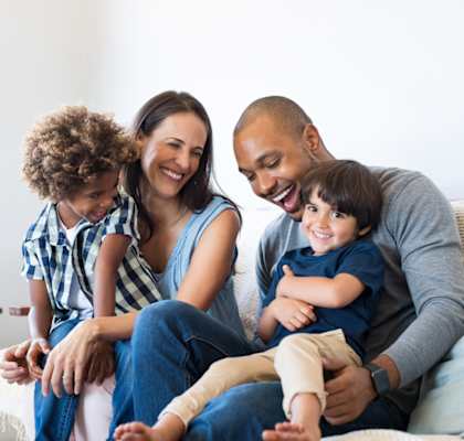 A family of four is sitting on a couch together.