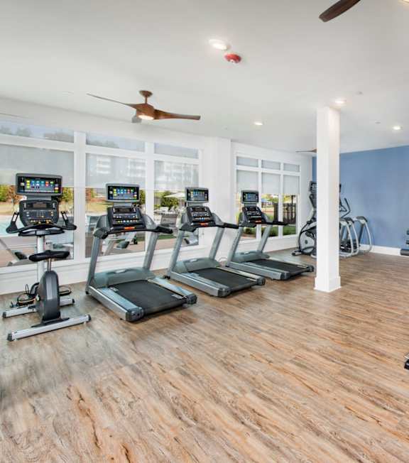 A spacious gym with a variety of equipment including treadmills, weights, and a bench press at The Barrett in Kennesaw, GA