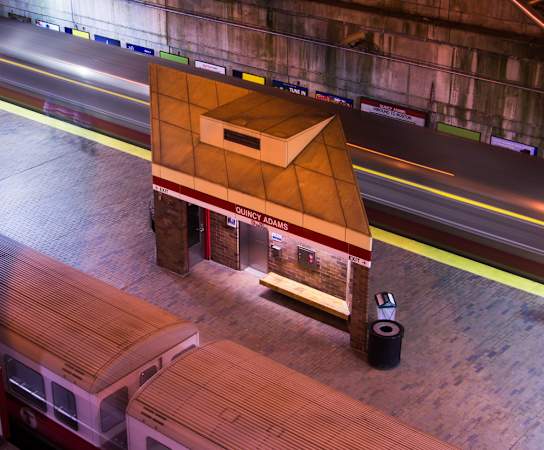 a train station with a small building on top of a platform at Highlands at Faxon Woods, Quincy, 02169