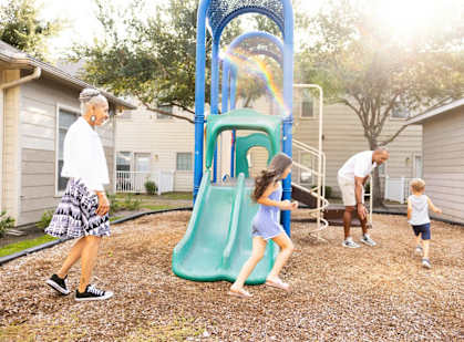 A woman and two children are playing on a playground.