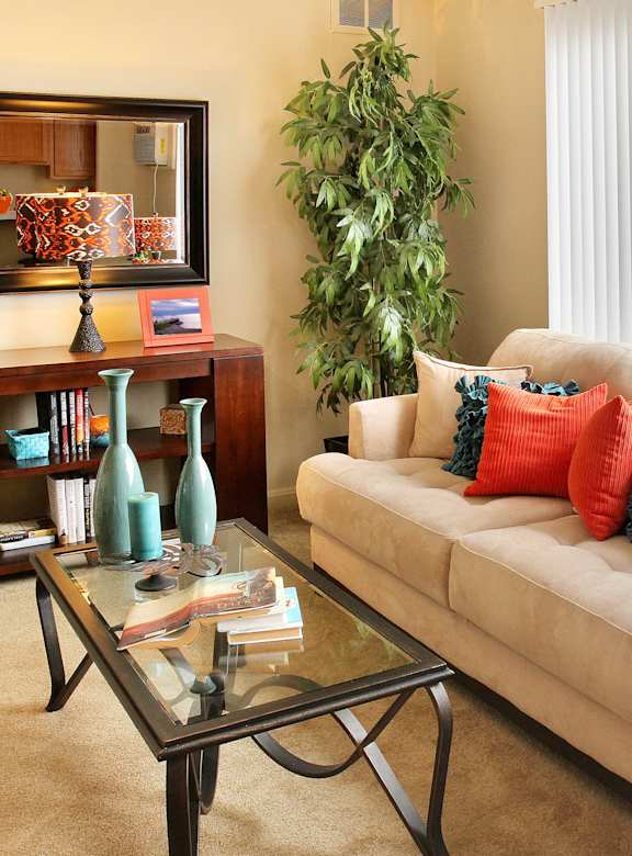 A living room with a couch, a coffee table, and a potted plant.