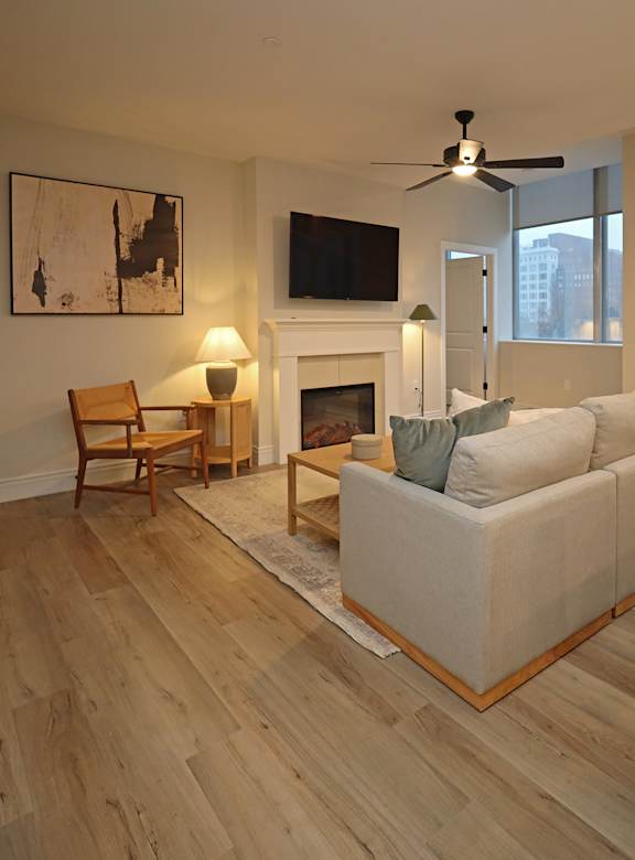 A living room with a white couch, a fireplace, and a painting on the wall.