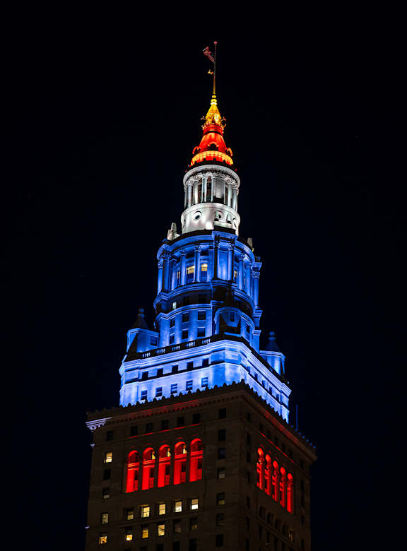 A tall building with a lit up spire at the top.