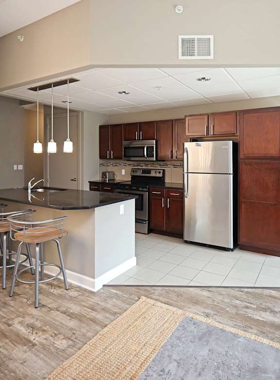A kitchen with a refrigerator, stove, and bar stools.