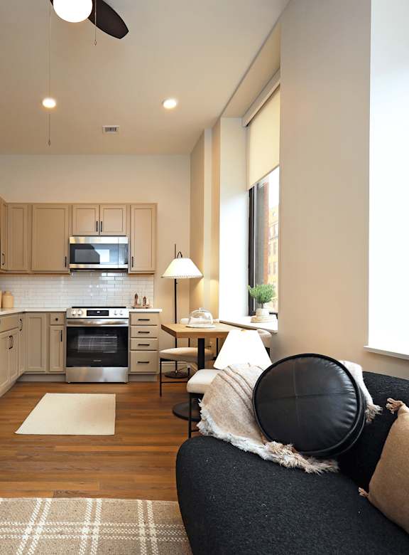 A modern kitchen with a black chair and a white ceiling fan.