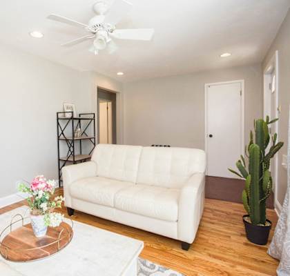 A white couch sits in a living room with a wooden coffee table in front of it.
