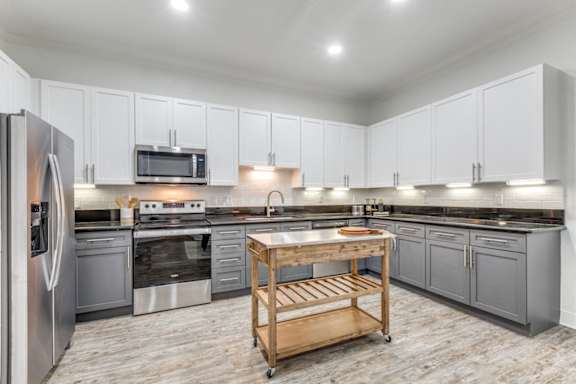 a large kitchen with stainless steel appliances and gray cabinets